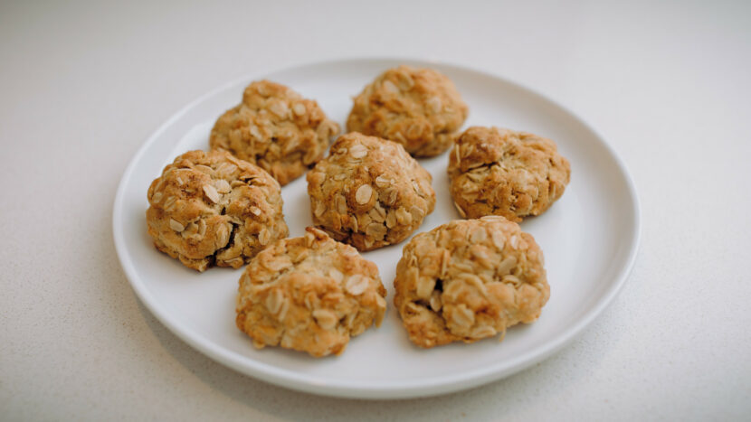 A small white plate with seven Anzac biscuits sitting on it